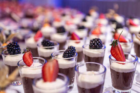Closeup many dessert jar rowed up on buffet table with fresh fruits jelly and cream