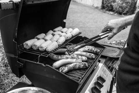 Freshly cooked sausages on a grill with corn close-up.