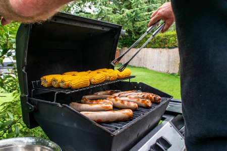 Freshly cooked sausages on a grill with corn close-up. Background of sausages made with charcoalの写真素材