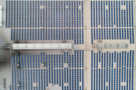 Aerial top down view on many Solar panels rows lined up on of factory roof.