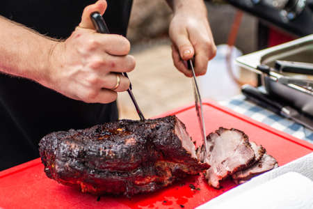 chef cook cutting smoked beef meat, Butcher cutting pork meat on kitchen tableの写真素材