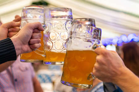 A group of young people Friends toasting with glasses of beer at the Oktoberfest germany Soft focus....