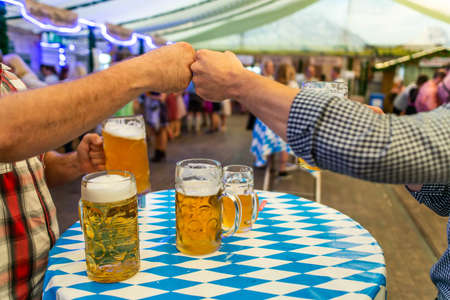 A group of young people Friends toasting with glasses of beer at the Oktoberfest germany Soft focus. Shallow DOF