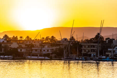 View of the Nile river with sailboats at golden colorful sunset in Luxor, Egyptの写真素材