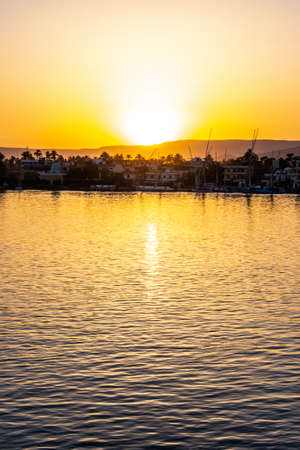 View of the Nile river with sailboats at golden colorful sunset in Luxor, Egyptの写真素材