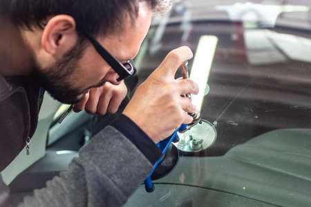 Koblenz Gerrmany 04.04.2018 man using repairing equipment to fix damaged cracked windshield at...