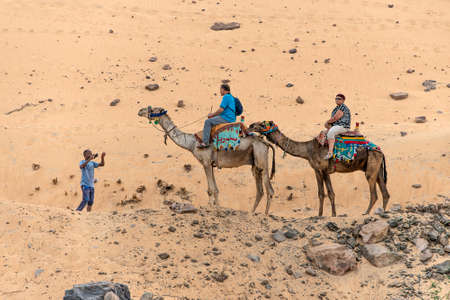 ASWAN,EGYPT 18.05.2018 Tourists aboard camel tour to Nubian village the west bank of the River Nile in the Aswan regionのeditorial素材