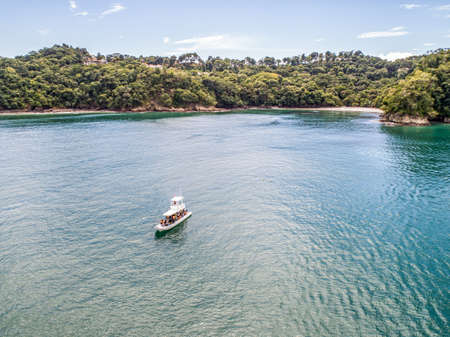 Manuel Antonio Costa Rica 02.11.2019 white fishing excurison boat anchoring in blue bay with empty beach Central Americaのeditorial素材