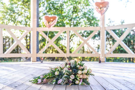 Wedding bouquet of flowers lying on the ground closeupwith love heart decoration in backgroundの写真素材