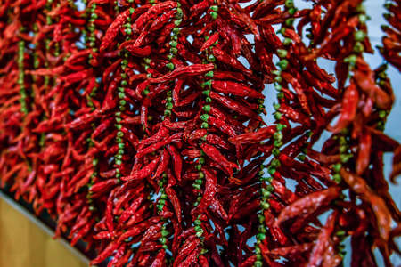 Close up view of hanging hot dried chili peppers on the local farmers market Mercado dos Lavradores...