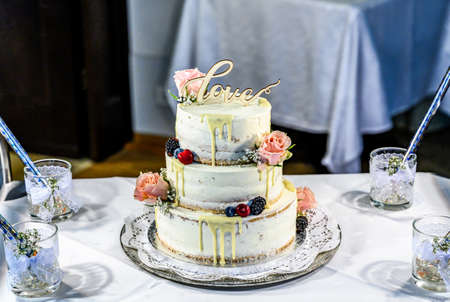 Beautiful wedding cake with cream With text Love on top and pink flowers rosesの写真素材