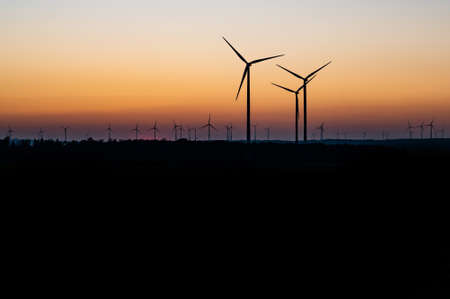 Black Silhouette of windturbines energy generator on amazing sunset at a wind farm in germanyの写真素材