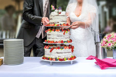Groom and bride marriage Cutting the delicious fruity Wedding Cake together colorful fruitsの写真素材