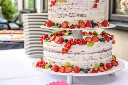 beautiful delicious Wedding cake in many tiers with fresh wild berries and fruits