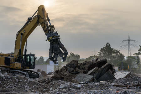 Building House Demolition site Excavator with hydraulic crasher machine and yellow container.
