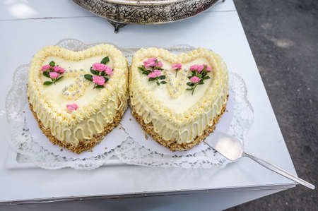 Romantic wedding Two cakes in heart shape, roses bouquet on white table background. Top viewの写真素材