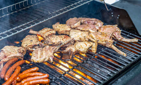 Tomahawk rib beef steak ans sausages on hot black grill with flames bbq