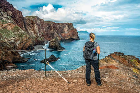 Girl hiking rocky cliffs clear near water of Atlantic Ocean bay Ponta de Sao Lourenco, the island of Madeira, Portugalの写真素材