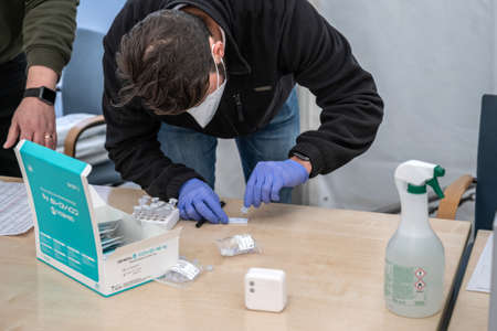 14.04.2021 Geneda Coronavirus COVID-19 diagnostic worker holding swab sample collection kit hand in gloves testingのeditorial素材