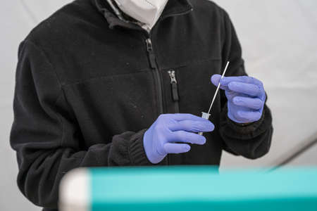 14.04.2021 Geneda Coronavirus COVID-19 diagnostic worker holding swab sample collection kit hand in gloves testingのeditorial素材