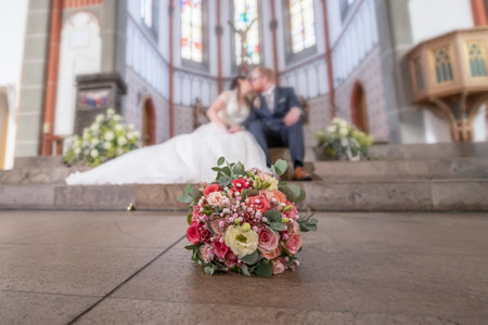 Wedding bouquet on foreground of a blurred kissing couple. Flowers and loversの写真素材