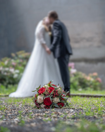Wedding bouquet on foreground of a blurred kissing couple. Flowers and loversの写真素材