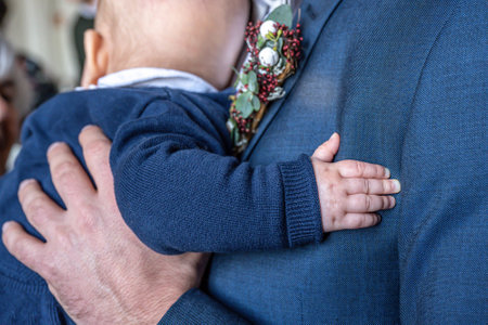 Close up of child hand holding groom body on weddingの写真素材