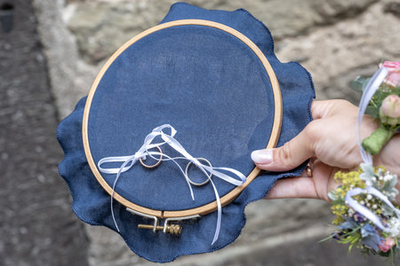 Close-up view of golden wedding rings on blank decorative stiching ring pillowの写真素材