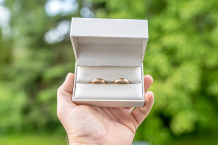 Elegant gold wedding rings lie among soft satin white ribbon. Front vertical view. Mockup for wedding postcardの写真素材