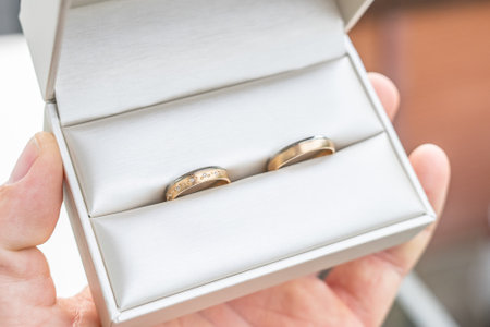 Elegant gold wedding rings lie among soft satin white ribbon. Front vertical view. Mockup for wedding postcardの写真素材