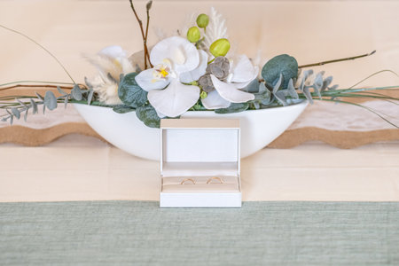 Elegant gold wedding rings lie among soft satin white ribbon. Front vertical view. Mockup for wedding postcardの写真素材