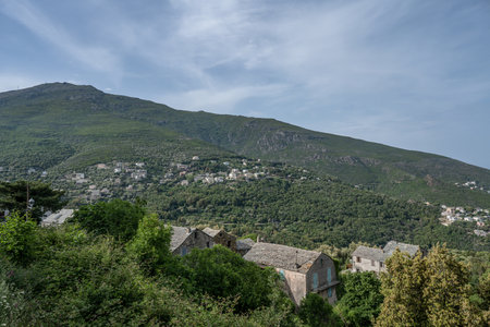 panoramic view village mountainous landscape towards the Gulf of Porto in sunlight with blue skies and spectacular cloudの写真素材