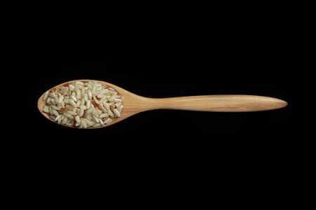 Pile of brown rice with spoon isolated on Black Backgroundの写真素材