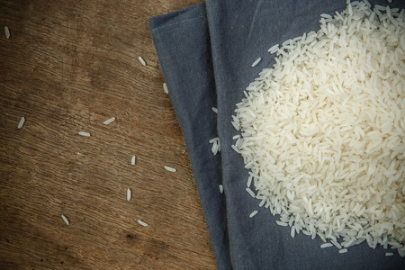 White rice grains with wooden spoon on wooden table - soft focusの写真素材