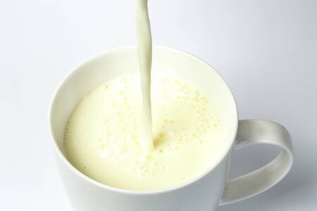Pouring a cup of milk creating splashの写真素材