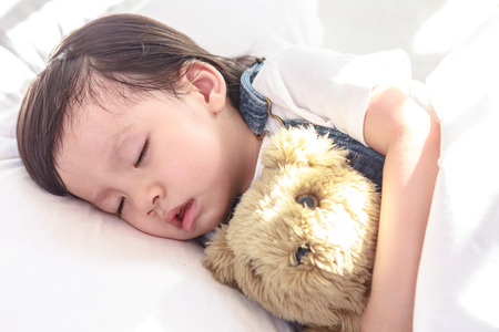 Little asian girl sleeping with her toy teddy bearの写真素材