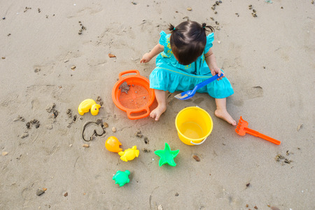 Cute little girl building sandcastle on tropical summer beachの写真素材