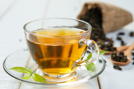 Warm cup of tea and leaves tea on white woodenの写真素材