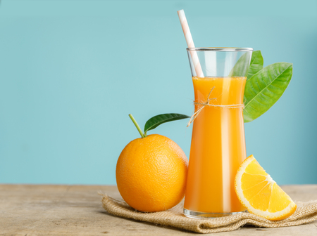 Glass of fresh orange juice on wooden table, Fresh fruits Orange juice in glass with group of orange on blue background, Selective focus on glassの写真素材