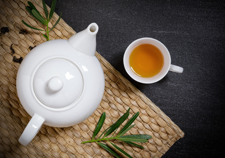 Cup of hot tea with steaming jugs and dry tea on the plate mat on the black stone table background with copy space for your text.の写真素材