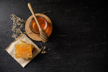 Honey bee and Honeycomb with honey dipper and dry flower on black background, bee products by organic natural ingredients conceptの写真素材