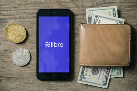 Smartphone with Libra logo on the screen and Cryptocurrency digital golden coins, Libra cryptocurrency in easy to use conceptの写真素材