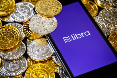 Smartphone with Libra logo on the screen and Cryptocurrency digital golden coins
