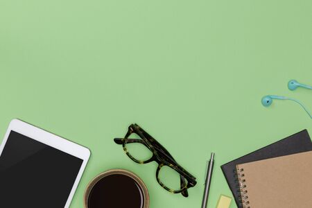 Creative flat lay of office supplies mockup with tablet, books and accessories isolated on green background, Top view with copy space, Workspace for freelancer conceptの写真素材