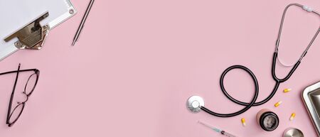 Creative flatlay of doctor medical equipment pink table with stethoscope, medical documents, thermometer, syringe and pills, Health care concept, isolated on colorful pink long banner backgroundの写真素材