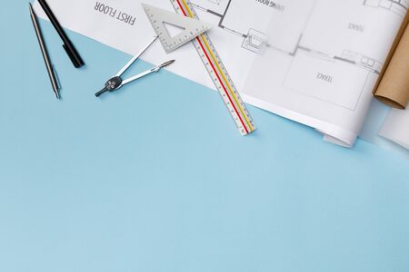 Creative flat lay of architects blue table with roll blueprints, architectural project plan,...