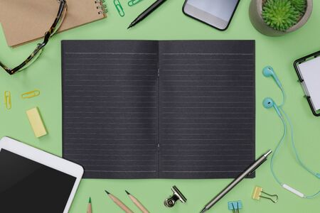 Top view workspace office supplies mockup with tablet, glasses, books and accessories isolated on green background, overhead view with copy space, Workspace for designer conceptの写真素材