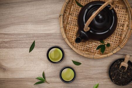 Cup of hot green tea with teapot, green tea leaves and dried herbs top view on the wooden table empty space, Organic product from the nature for healthy with traditional styleの写真素材