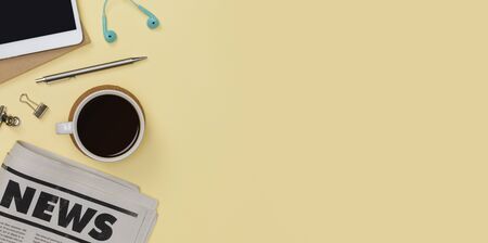 Creative flat lay of office supplies mockup with tablet, newspaper, hot coffee cup, books and accessories isolated on yellow background, Top view with copy space, Workspace for freelancer conceptの写真素材