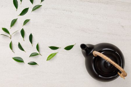 Teapot with organic green tea leaves on the white stone desk empty space creative flat lay, Organic product from the nature for healthy with traditional styleの写真素材